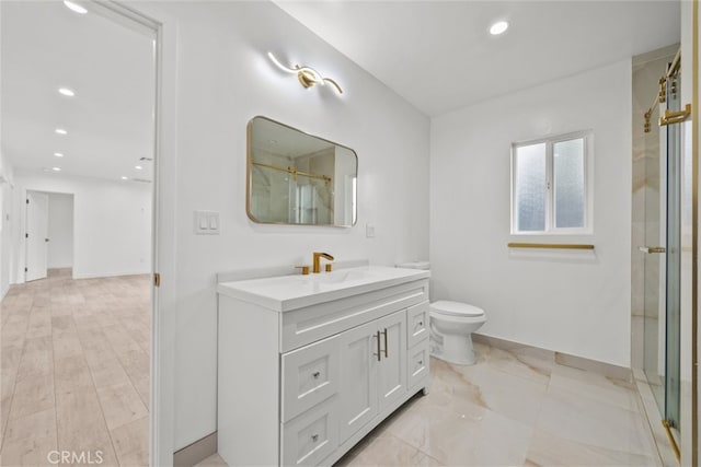 bathroom featuring toilet, a shower with door, recessed lighting, baseboards, and vanity