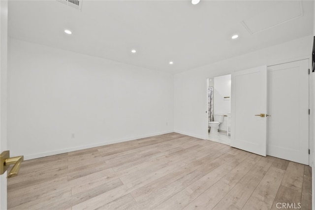 spare room featuring recessed lighting, attic access, light wood-type flooring, and baseboards