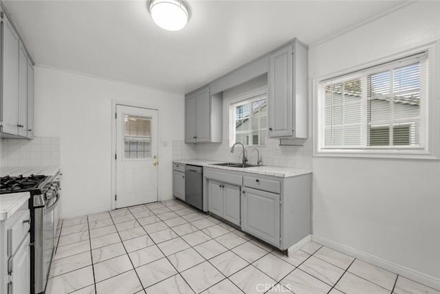 kitchen featuring baseboards, a sink, gray cabinetry, stainless steel appliances, and backsplash