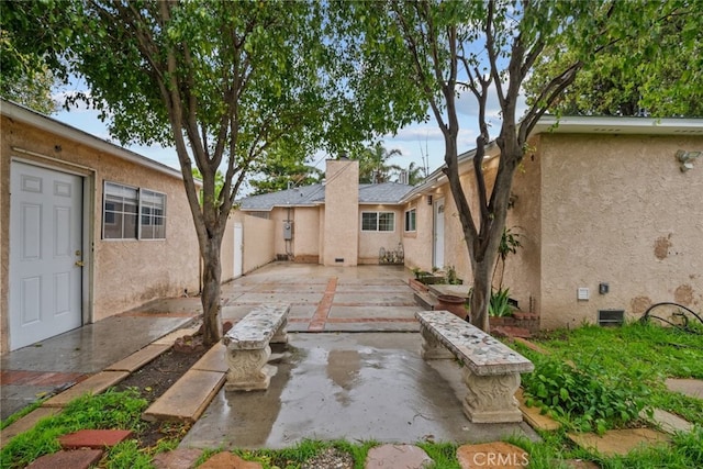 back of house featuring stucco siding, a chimney, a patio, and fence