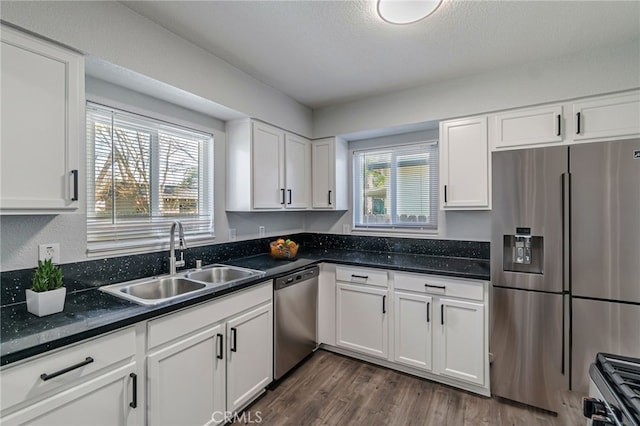 kitchen featuring plenty of natural light, a sink, stainless steel appliances, dark wood-type flooring, and white cabinetry