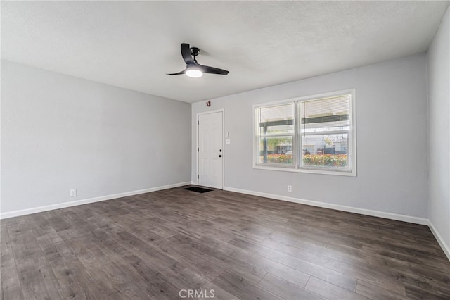 empty room featuring dark wood-style floors, ceiling fan, a textured ceiling, and baseboards