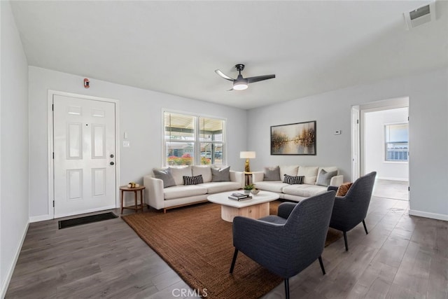 living room with visible vents, baseboards, dark wood-type flooring, and ceiling fan