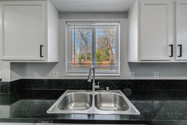 kitchen featuring a sink, dark countertops, and white cabinets