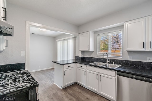 kitchen featuring a sink, stainless steel dishwasher, wood finished floors, white cabinetry, and gas stove