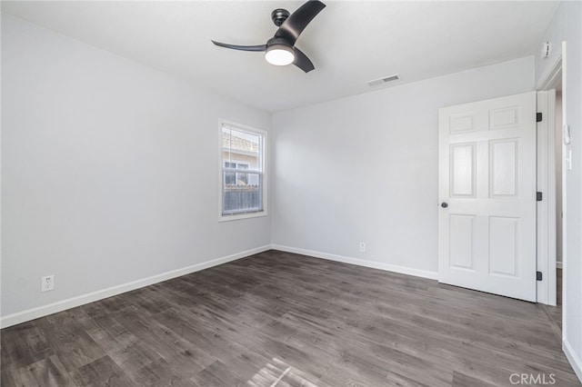 unfurnished room featuring dark wood-type flooring, visible vents, baseboards, and ceiling fan