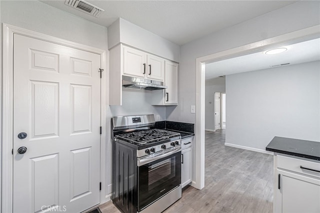 kitchen with visible vents, under cabinet range hood, light wood-type flooring, gas stove, and white cabinetry