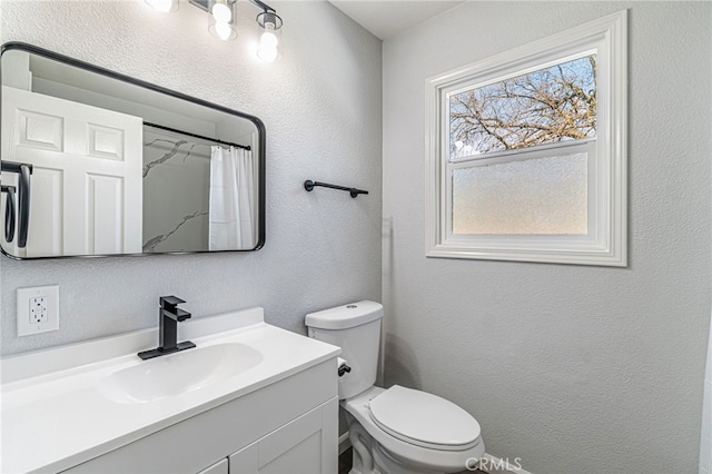 full bath featuring vanity, a shower with shower curtain, toilet, and a textured wall