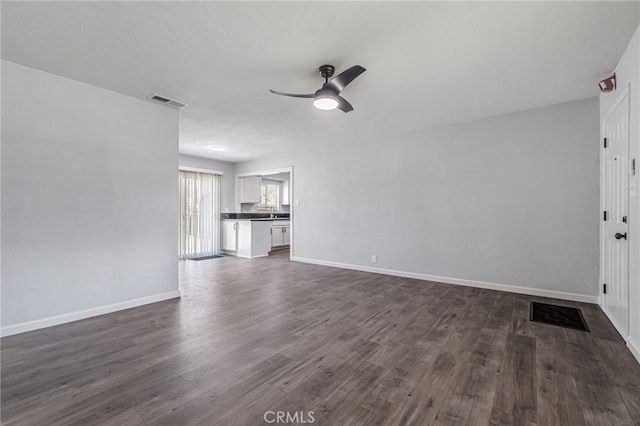 unfurnished living room with dark wood-style floors, visible vents, baseboards, and ceiling fan