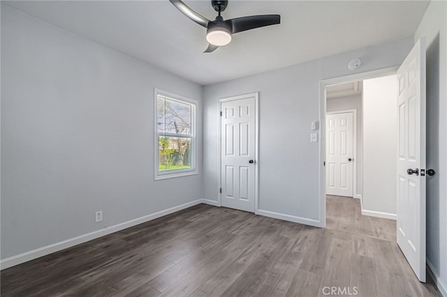 unfurnished bedroom featuring a ceiling fan, wood finished floors, baseboards, and a closet