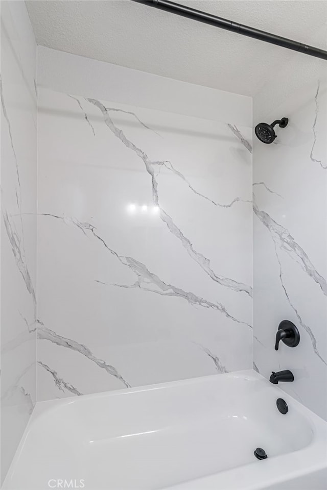 bathroom with tub / shower combination and a textured ceiling