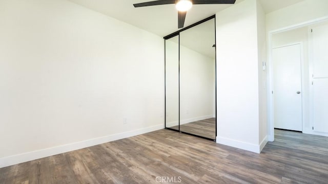 unfurnished bedroom with a ceiling fan, wood finished floors, baseboards, and a closet