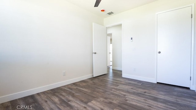 unfurnished bedroom with visible vents, baseboards, dark wood-type flooring, and a ceiling fan