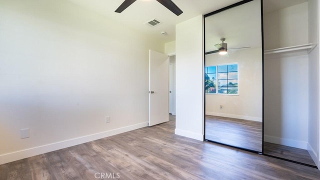 unfurnished bedroom featuring a ceiling fan, wood finished floors, visible vents, baseboards, and a closet