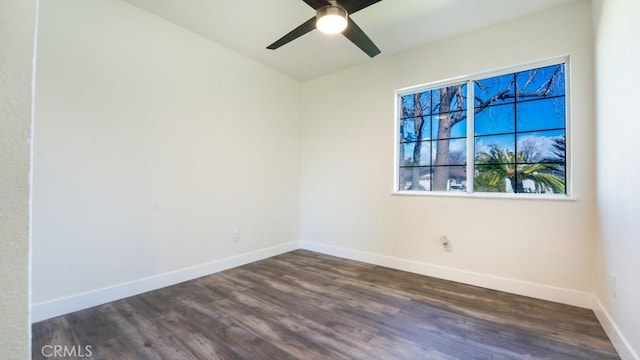 spare room featuring a ceiling fan, dark wood-style floors, and baseboards