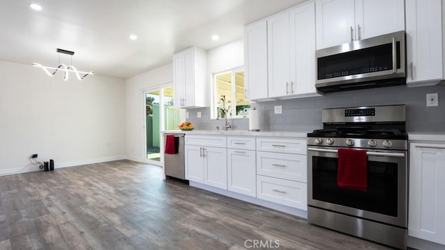 kitchen featuring dark wood-style floors, a sink, light countertops, appliances with stainless steel finishes, and tasteful backsplash