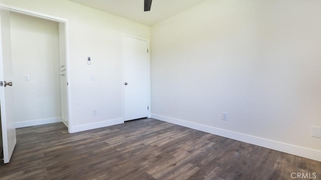 unfurnished bedroom featuring dark wood-type flooring, a ceiling fan, baseboards, and a closet