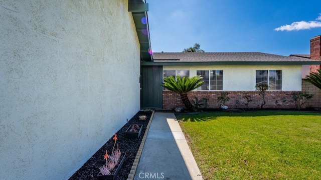 view of side of home with brick siding, stucco siding, and a yard