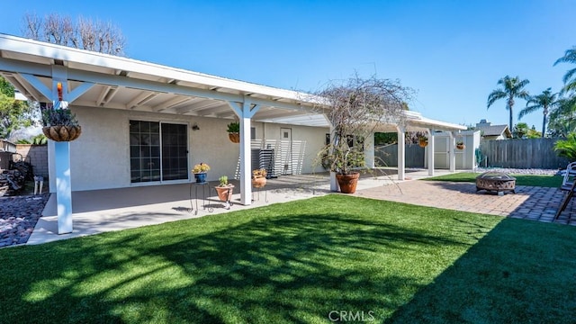 back of property with stucco siding, a fire pit, a patio area, and fence