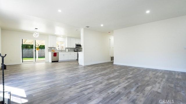 unfurnished living room with recessed lighting, baseboards, and wood finished floors