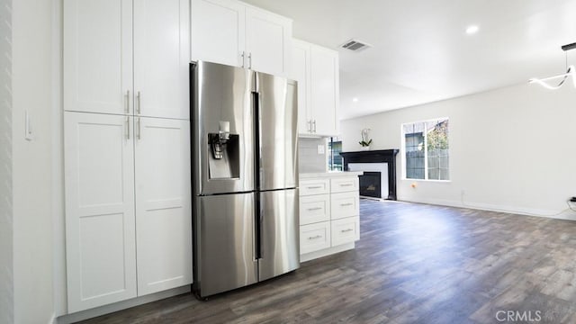 kitchen with dark wood-style floors, visible vents, a fireplace, white cabinets, and stainless steel refrigerator with ice dispenser