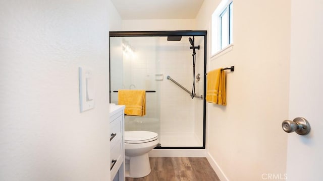 bathroom featuring a stall shower, toilet, baseboards, and wood finished floors