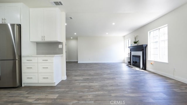 unfurnished living room with visible vents, dark wood-type flooring, a glass covered fireplace, recessed lighting, and baseboards