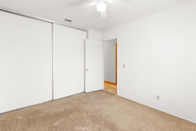 unfurnished bedroom with a closet, visible vents, carpet floors, and ceiling fan