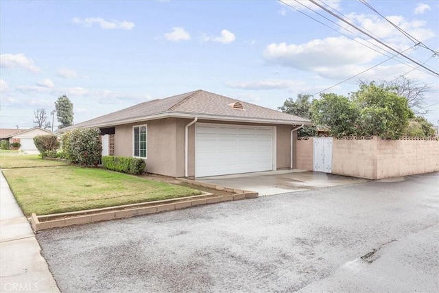 exterior space with fence, stucco siding, a lawn, a garage, and driveway