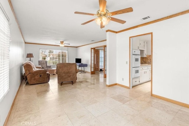 living room featuring visible vents, a ceiling fan, crown molding, and baseboards