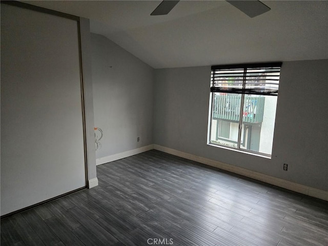 empty room with baseboards, lofted ceiling, dark wood-type flooring, and ceiling fan