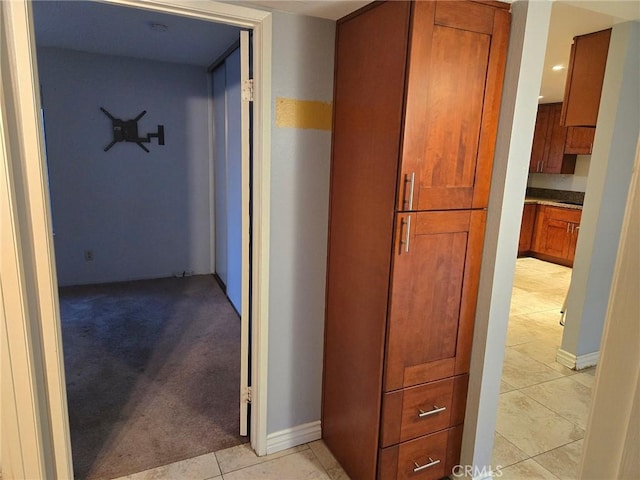 corridor featuring light tile patterned flooring and light colored carpet