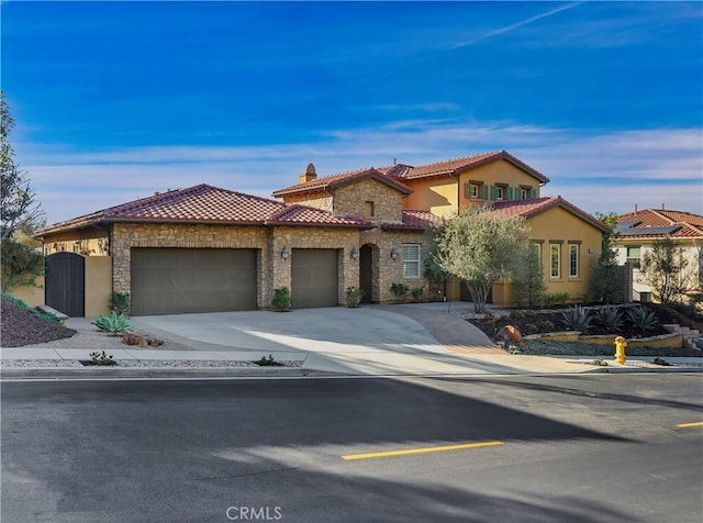 mediterranean / spanish home with stone siding, a tiled roof, concrete driveway, and a garage