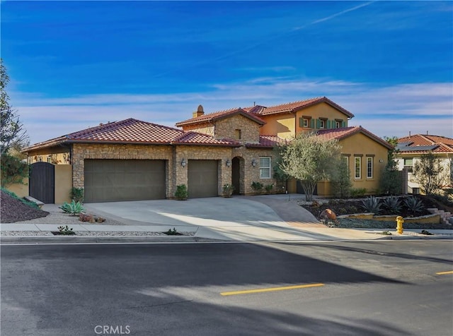 mediterranean / spanish-style home with driveway, an attached garage, stucco siding, stone siding, and a tiled roof