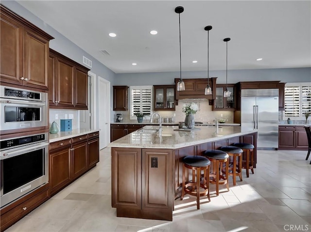 kitchen with decorative backsplash, a sink, a spacious island, stainless steel appliances, and glass insert cabinets