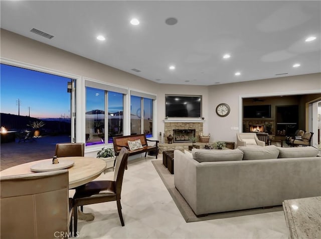 living area featuring a stone fireplace, recessed lighting, and visible vents