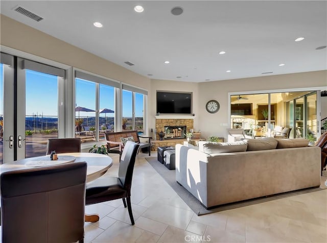 living room with visible vents, a ceiling fan, recessed lighting, a stone fireplace, and light tile patterned flooring