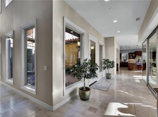 hall featuring recessed lighting, visible vents, baseboards, and light tile patterned floors