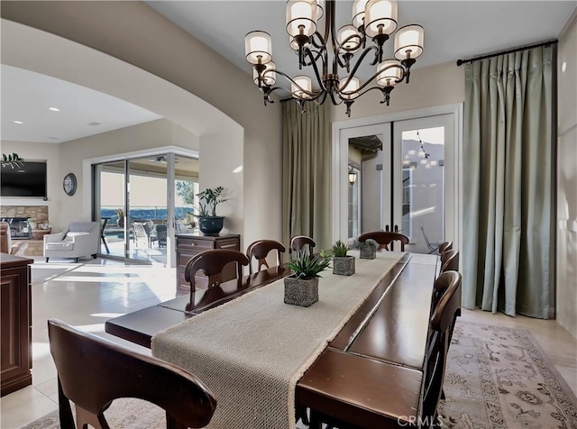 dining area featuring arched walkways, a notable chandelier, and a fireplace