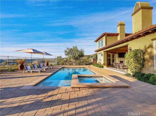 view of pool with fence, a pool with connected hot tub, and a patio area