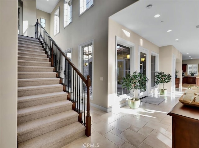 foyer entrance with recessed lighting, stairway, baseboards, and a towering ceiling