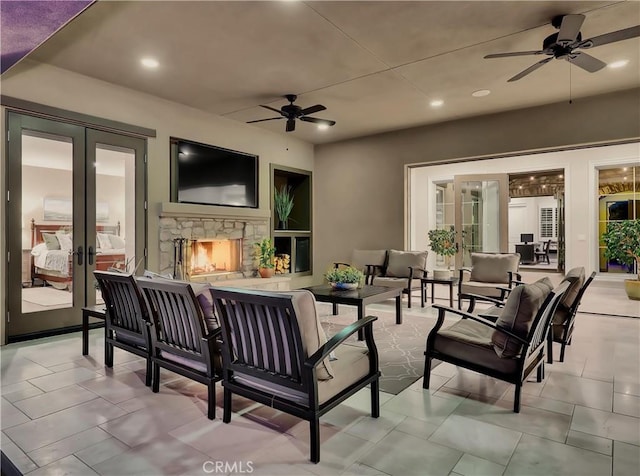 view of patio / terrace featuring french doors, an outdoor living space with a fireplace, and ceiling fan