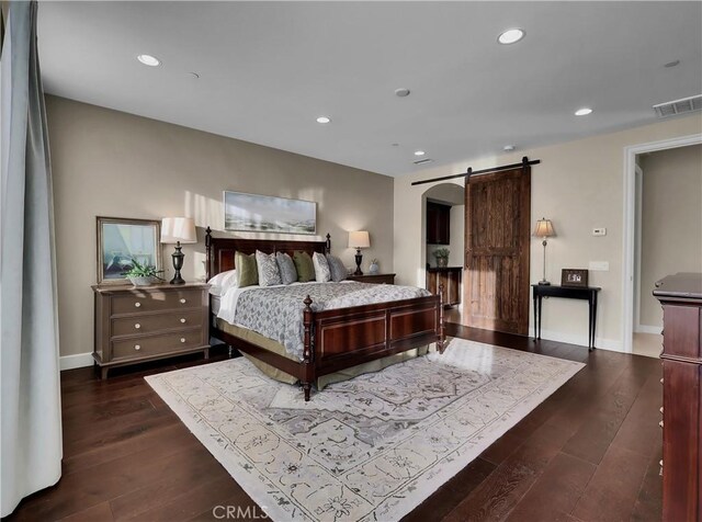 bedroom featuring visible vents, recessed lighting, a barn door, baseboards, and dark wood-style flooring