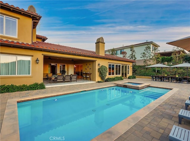 view of pool featuring an outdoor living space, a pool with connected hot tub, and a patio