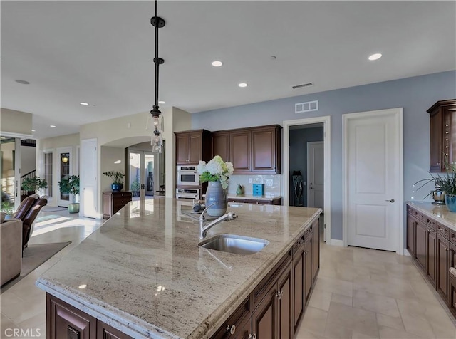 kitchen with visible vents, a sink, open floor plan, arched walkways, and separate washer and dryer