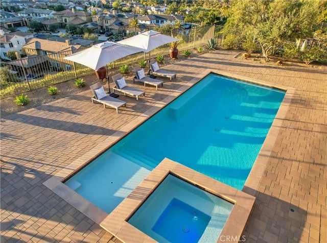 view of pool featuring a patio, a fenced backyard, a residential view, and a pool with connected hot tub