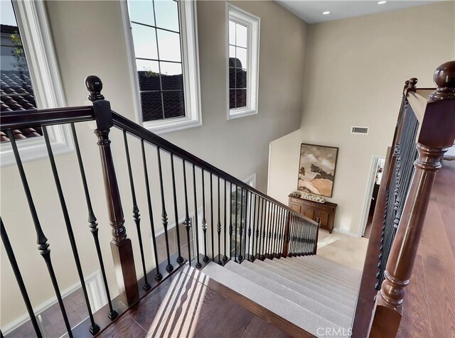 stairway featuring recessed lighting, wood finished floors, and visible vents