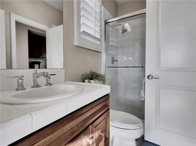 full bathroom featuring vanity, a stall shower, and toilet