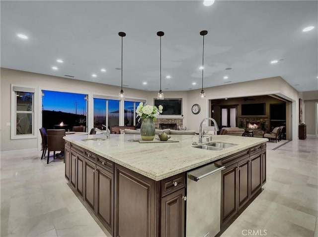 kitchen with a stone fireplace, open floor plan, stainless steel dishwasher, and a sink