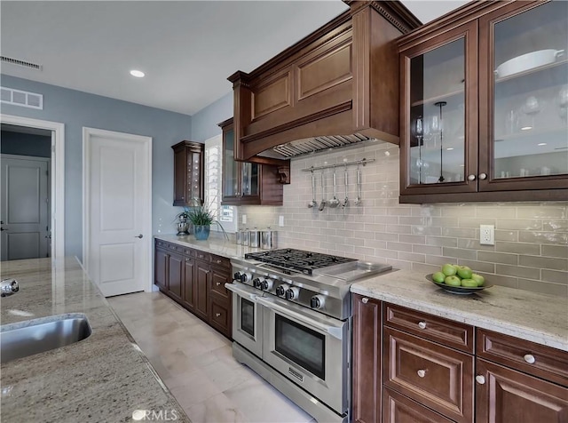 kitchen featuring light stone counters, visible vents, a sink, and range with two ovens